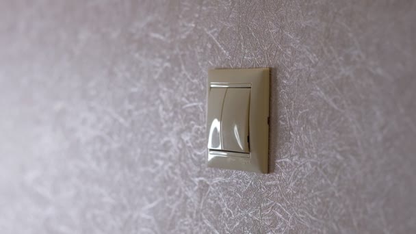 A luz está desligada - a mão feminina desliga um botão em uma parede cinza-clara, vista lateral
 - Filmagem, Vídeo