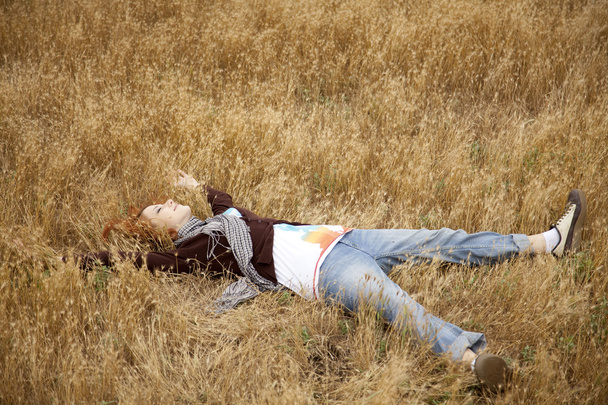 Young beautiful girl lying at yellow autumn field. - Fotó, kép