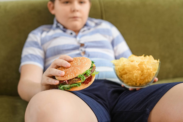 Nadwaga chłopiec z niezdrowym jedzeniem w domu - Zdjęcie, obraz