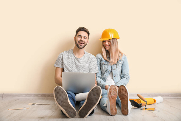 Young couple with laptop planning repair of their new apartment - Photo, Image