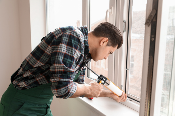 Miespuolinen työntekijä asentamassa ikkunaa tasaiseen
 - Valokuva, kuva