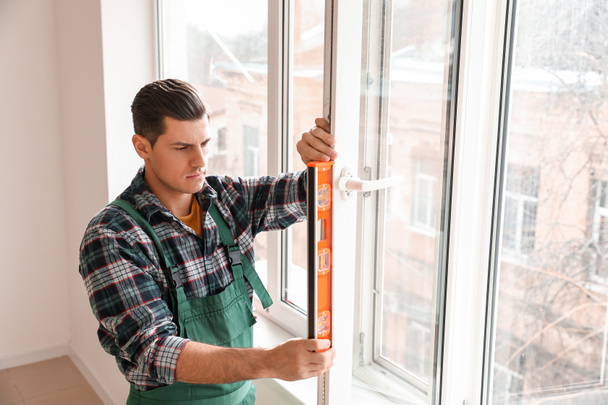 Άνδρας εργαζόμενος εγκατάσταση παράθυρο σε επίπεδη - Φωτογραφία, εικόνα
