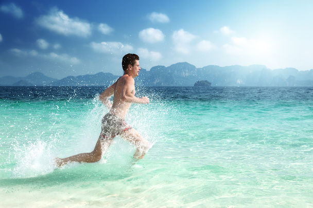 running man in water of tropical sea - 写真・画像