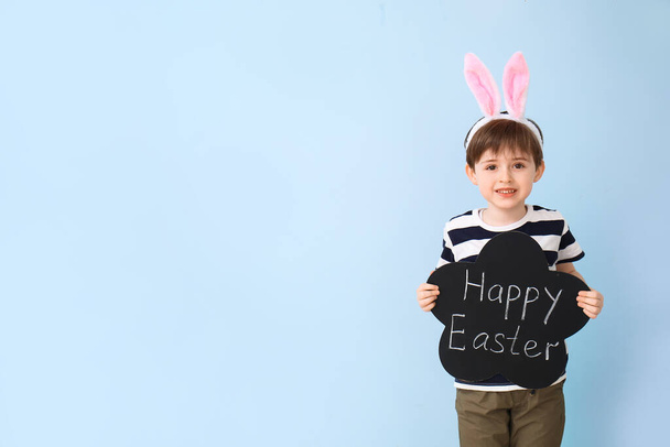 Mały chłopiec trzyma tablicę z tekstem HAPPY EASTER na tle koloru - Zdjęcie, obraz