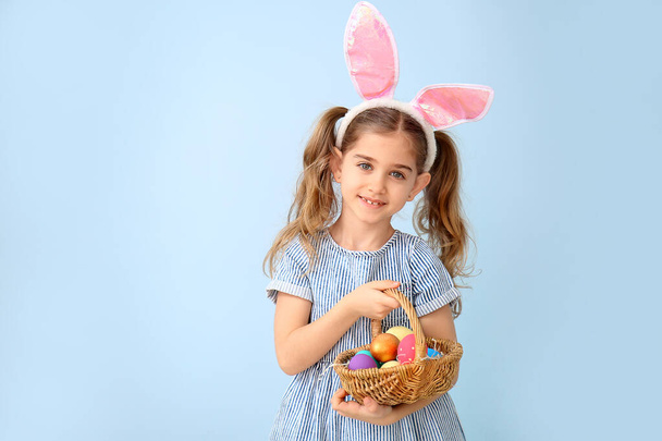 Niña con huevos de Pascua y orejas de conejo sobre fondo de color
 - Foto, imagen
