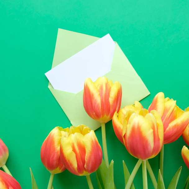 A bouquet of tulips and an envelope with a note on a green background. Concept of international women's day, mother's day, Easter - Foto, immagini