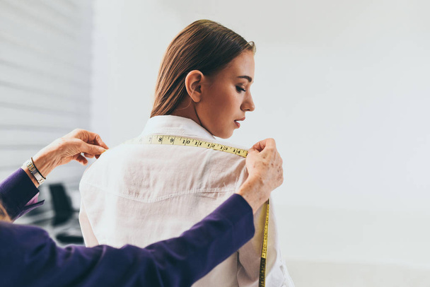 Fashion designer studio measuring textile material scissors cutting fabric by woman designer stylish showroom / designer working professional measuring a clothing for tailoring model woman in workshop - 写真・画像