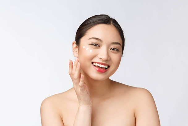 Skin care beauty woman. Beauty woman smiling applying cream. Beauty portrait of beautiful Asian Caucasian female model isolated on white. - Photo, Image