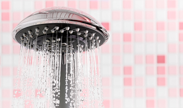 Shower head with flowing water stream in pink bathroom - Φωτογραφία, εικόνα