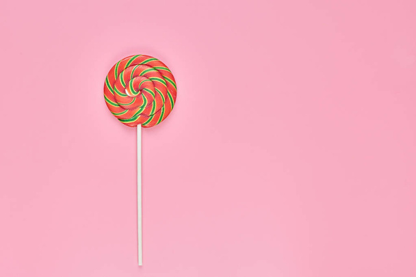 Sweet lollipop on pink background, copy space. Love to colorful sweetmeats in childhood concept - Photo, image