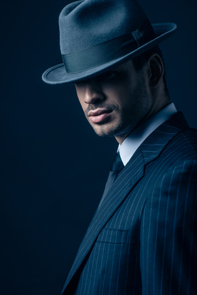Mafioso in suit and felt hat on dark blue background - Photo, Image