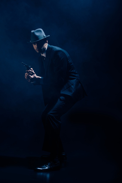 Gangster with weapon in clenched hands on dark background - Photo, Image