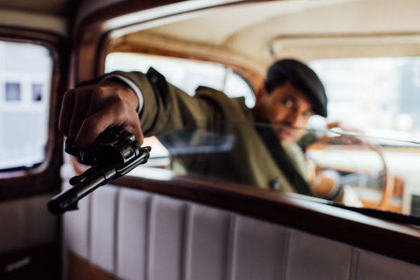 Selective focus of dangerous gangster aiming revolver in car - Foto, Imagen