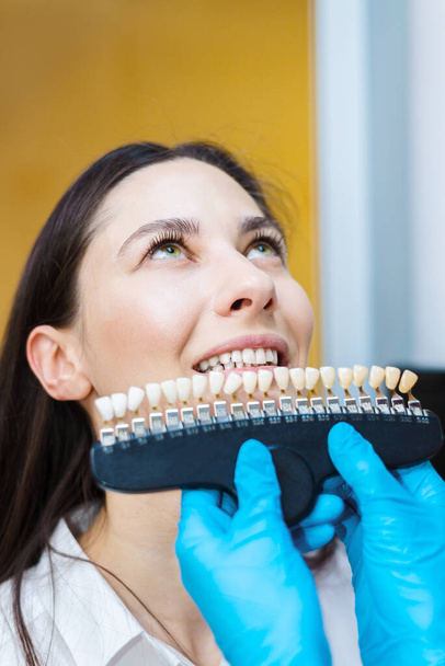 dentist checks teeth. Doctor holds color samples for teeth whitening. oral hygiene concept - Fotó, kép
