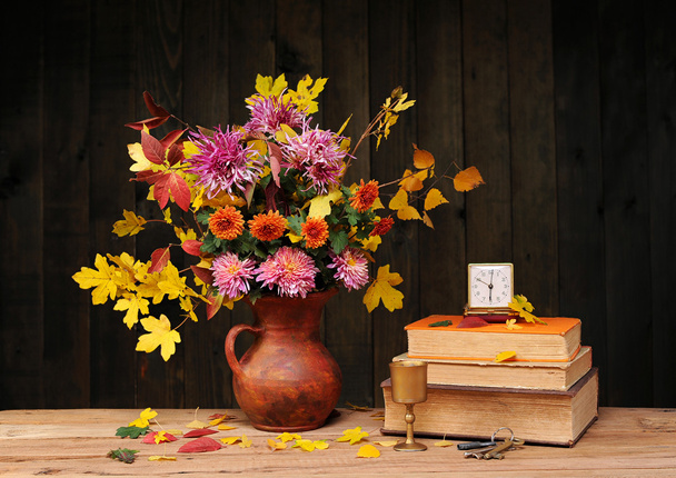 Flores em um vaso, livros e relógio
 - Foto, Imagem