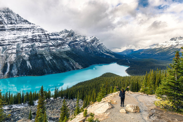 カナダのバンフ国立公園で女性旅行者が腕を上げたキツネに似ているペイトー湖の風景 - 写真・画像