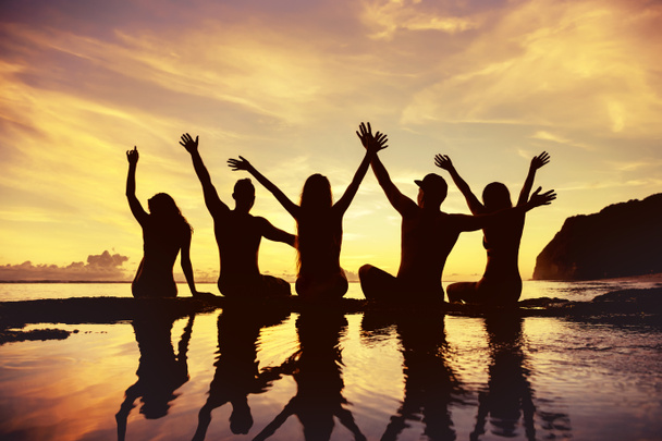 Amici felici con le braccia alzate contro il cielo del tramonto e la spiaggia
 - Foto, immagini