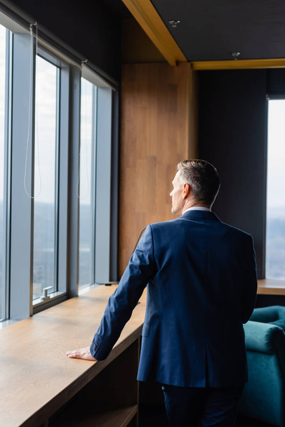 back view of businessman in suit looking through window  - Foto, imagen