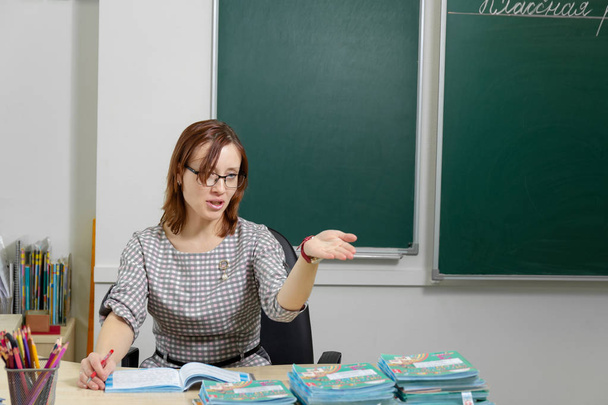 iskolai tanár nő az osztályteremben a táblán elkezd leckét felirat osztálymunka - Fotó, kép