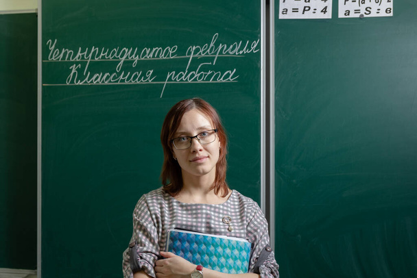 school teacher woman in classroom at blackboard starts lesson inscription february fourteenth classwork - Photo, Image