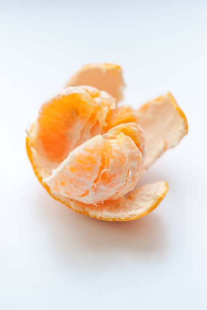 mandarina naranja madura con cáscara abierta sobre una mesa blanca
 - Foto, imagen