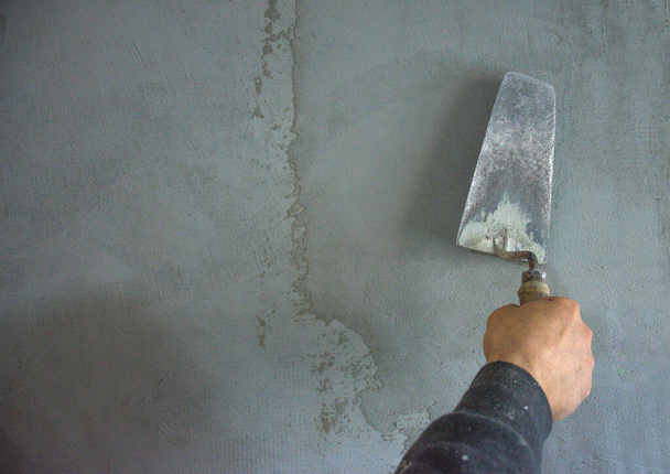Worker hand plastering and smoothing concrete wall with cement and a steel trowel, on construction site - Photo, Image