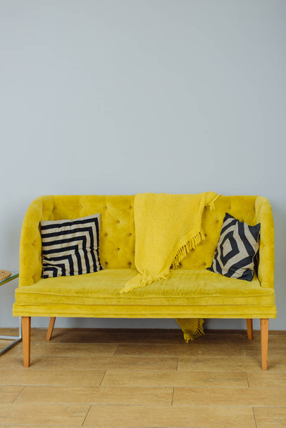 Beautiful yellow sofa with black and white pillows on a gray background - Photo, image