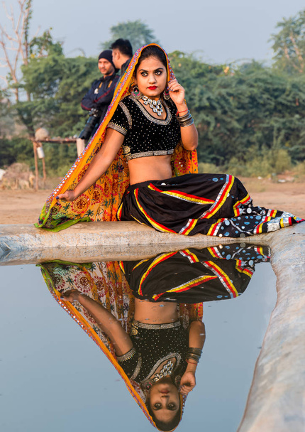Pushkar, Rajasthan / Ινδία - Νοέμβριος 2019: Πορτρέτο της νεαρής Ινδής όμορφη γυναίκα σε εθνοτική rajasthani φόρεμα απολαμβάνοντας τον πολιτισμό και την δίκαιη του pushkar - Φωτογραφία, εικόνα