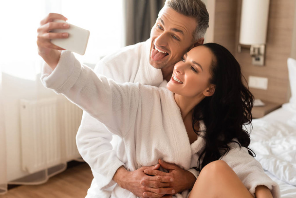 poikaystävä törröttää kielen ja tyttöystävä ottaa selfie hotellissa
 - Valokuva, kuva