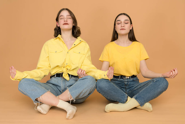 Portrait of funny cute charming ladies have meditation asana incredible zen sitting in lotus position impressed isolated dressed modern outfit on pastel background - Foto, imagen