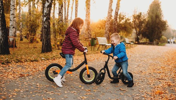 秋のカラフルな日に公園で自転車に乗るジーンズを着た素敵な白人の子供たち - 写真・画像