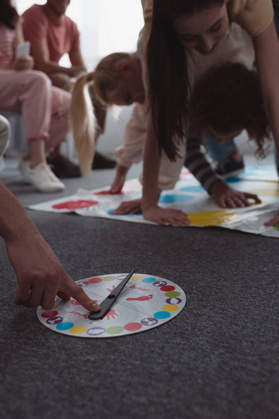 KYIV, UKRAINE - JANUARY 27, 2020: cropped view of man touching moves board while girls playing twister game - Foto, Bild