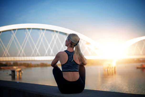 Portrait of fitness woman after workout in the city. Background bridge. Fitness, sport and healthy lifestyle concept. - Photo, Image