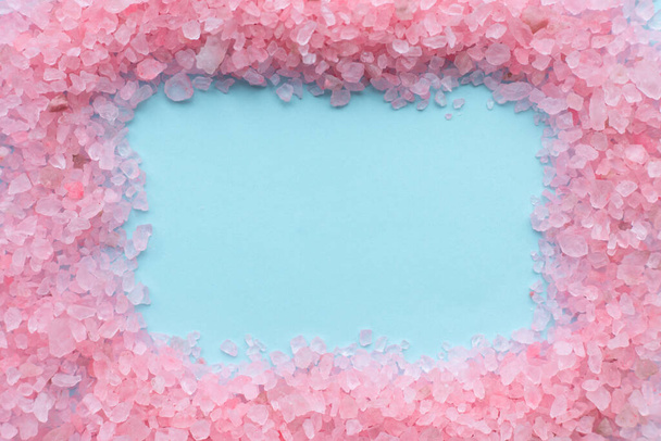 frame of coarse crystals of pink sea salt on a blue background with place for text - Fotó, kép