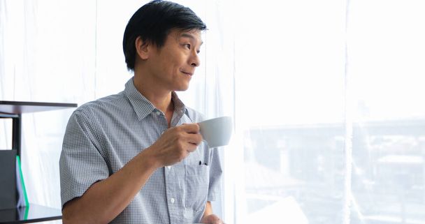 Vanhempi aasialainen mies juo kahvia rentouttavana aikana
 - Valokuva, kuva