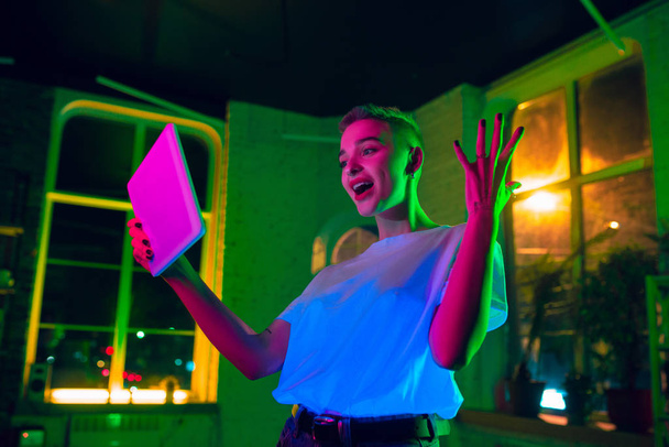 Cinematic portrait of handsome young woman in neon lighted interior - Foto, afbeelding