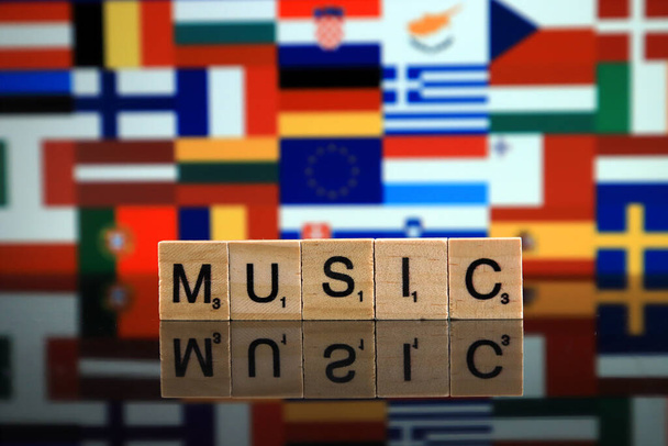 WROCLAW, POLAND - FEBRUARY 19, 2020: Word MUSIC made of wooden letters, and EUROPEAN UNION FLAG with flags of member countries in the background. - Photo, image