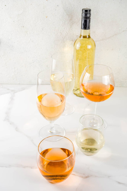 Moderní oranžové víno s bílým vínem v různých skleničkách, bílá betonová kopie v pozadí - Fotografie, Obrázek