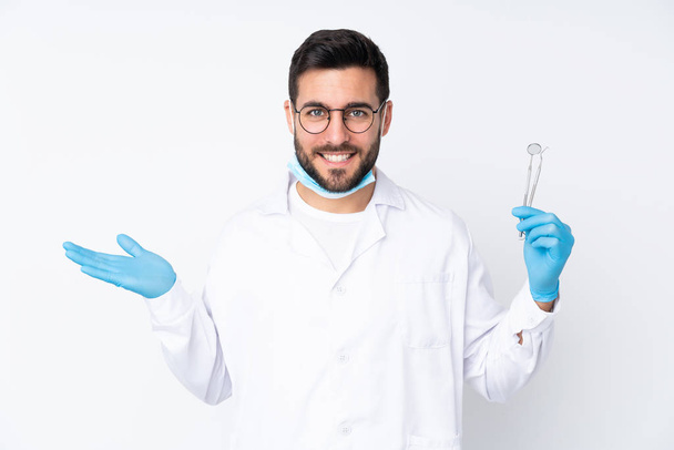 Οδοντίατρος κρατώντας εργαλεία που απομονώνονται σε λευκό φόντο κρατώντας copyspace φανταστικό στην παλάμη - Φωτογραφία, εικόνα