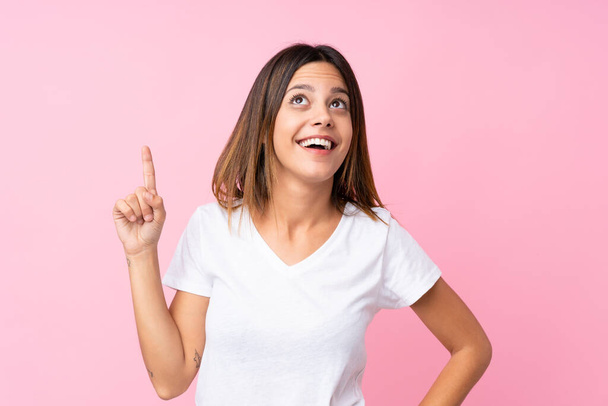 Young woman over isolated pink background intending to realizes the solution while lifting a finger up - Foto, afbeelding