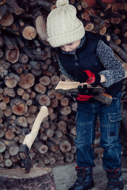 One little boy chopping firewood in the front yard at the day time. Kid having fun outdoors. Concept happy lifestyle. - Фото, зображення