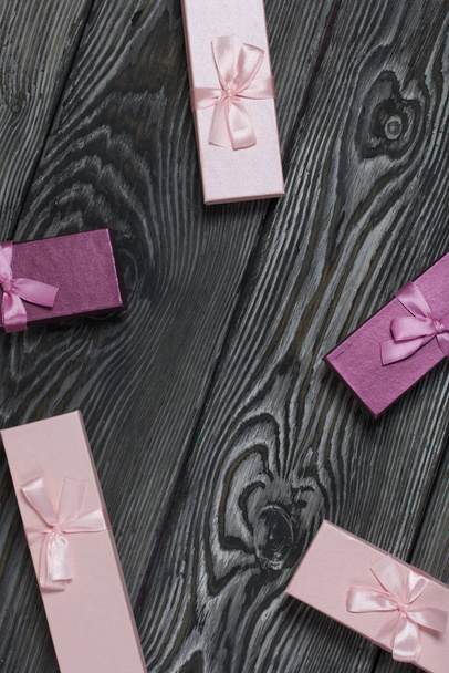 Cardboard boxes with gifts. Pink and lilac, decorated with ribbon bows. Lying on the background of brushed pine boards. - Foto, Imagem