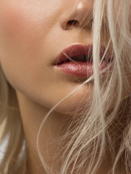 Sexual full lips. Natural gloss of lips and woman's skin. The mouth is closed. Increase in lips, cosmetology. Pink lips and long neck. Gentle pure skin and wavy blonde hair. - 写真・画像