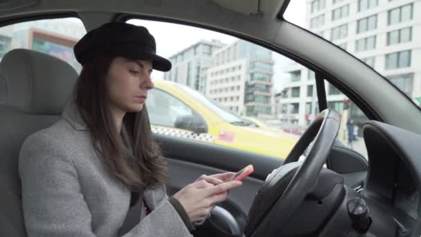 Dziewczyna używająca smartfona w samochodzie i sprawdzająca lusterko wsteczne  - Materiał filmowy, wideo
