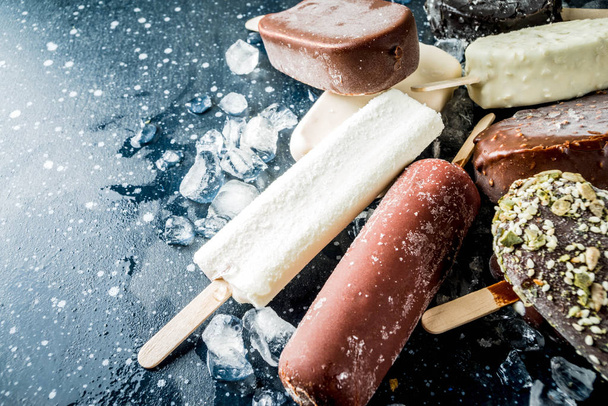 Surtido de varios helados de paleta, vainilla y chocolate, con nueces, sobre un fondo de hormigón oscuro con hielo, vista superior del espacio de copia
 - Foto, imagen