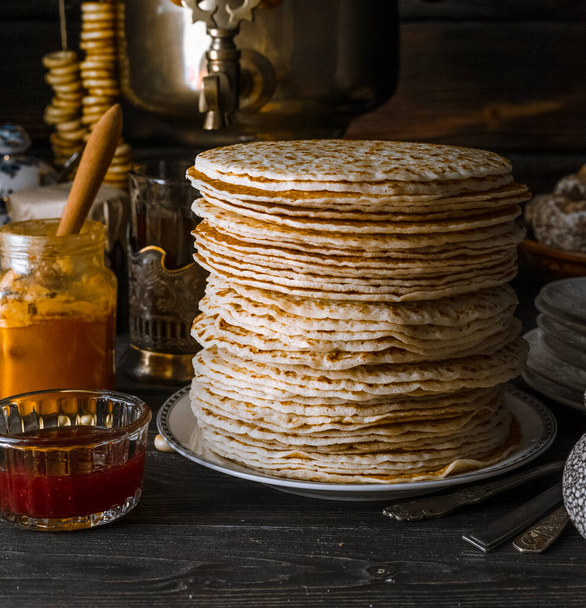 Shrovetide Maslenitsa Butter Week festival meal. Stacked russian pancakeswith jam on dark rustic background. Closeup view, portrait orientation - Photo, Image