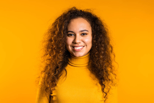 Young curly woman in total yellow look. Portrait of beautiful mixed race girl on studio background. Close up - Фото, зображення