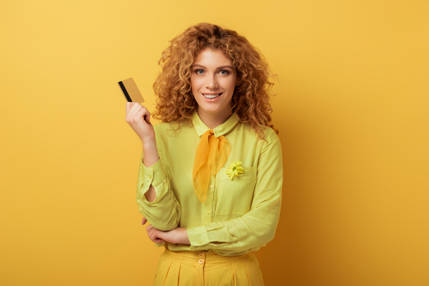 sourire rousse fille tenant carte de crédit sur jaune
  - Photo, image