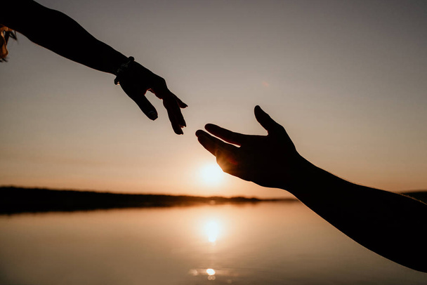 Молодая пара обнимается в воде на Сансет. Два силуэта рук против солнца. Романтическая история любви
. - Фото, изображение