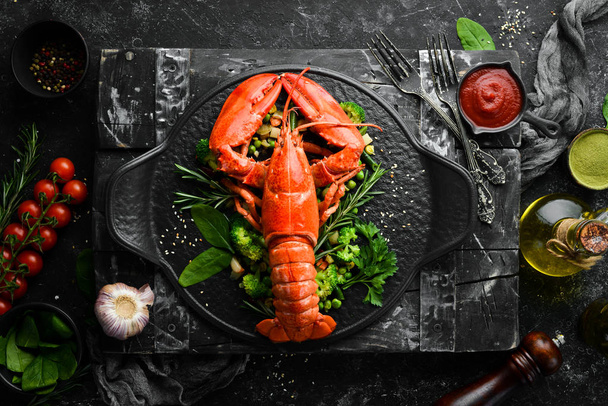 Boiled lobster with vegetables on a black stone plate. Seafood. Top view. Free space for your text. - Фото, зображення